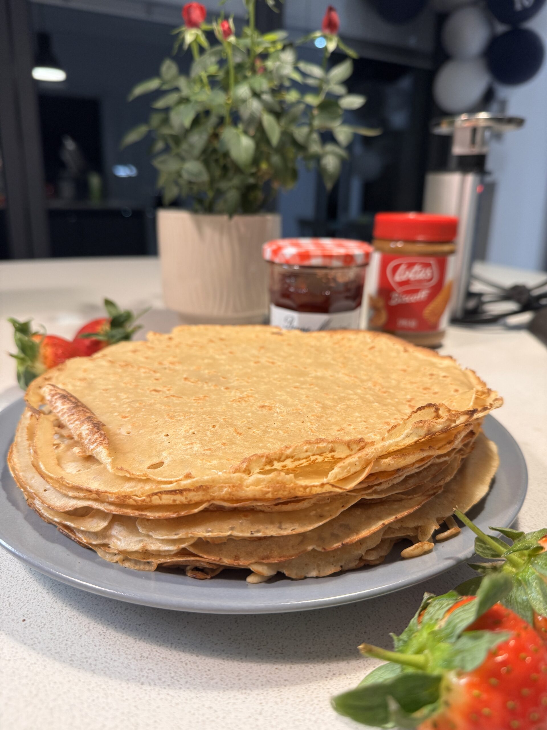 Pile of crepes with strawberries and strawberry jam